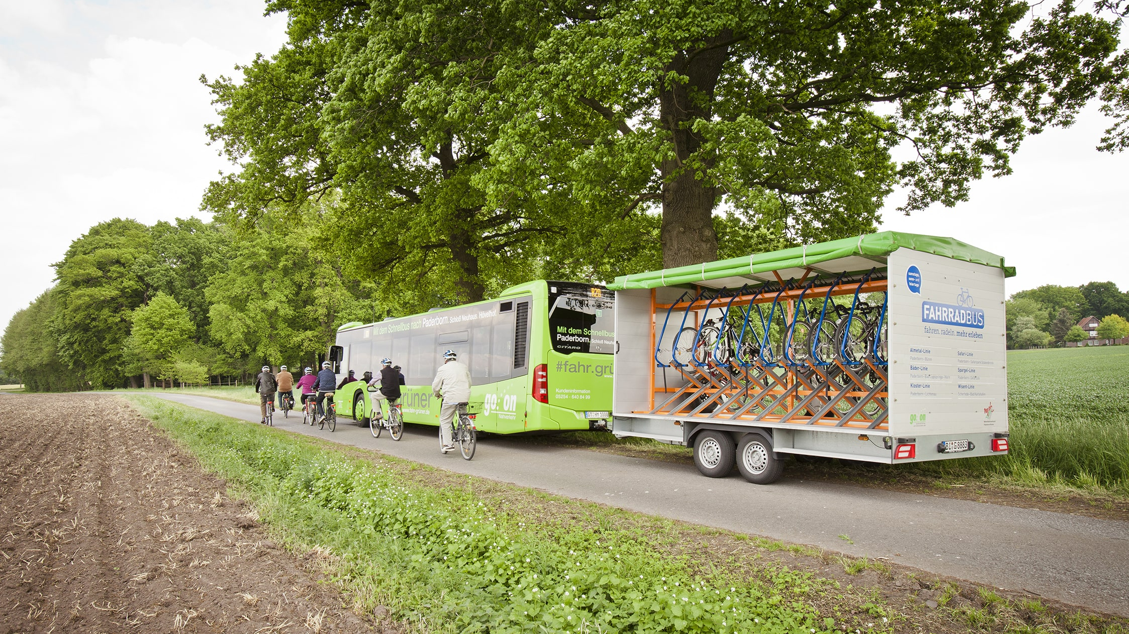 Auf einem Feldweg steht ein Bus mit Fahrradanhänger.