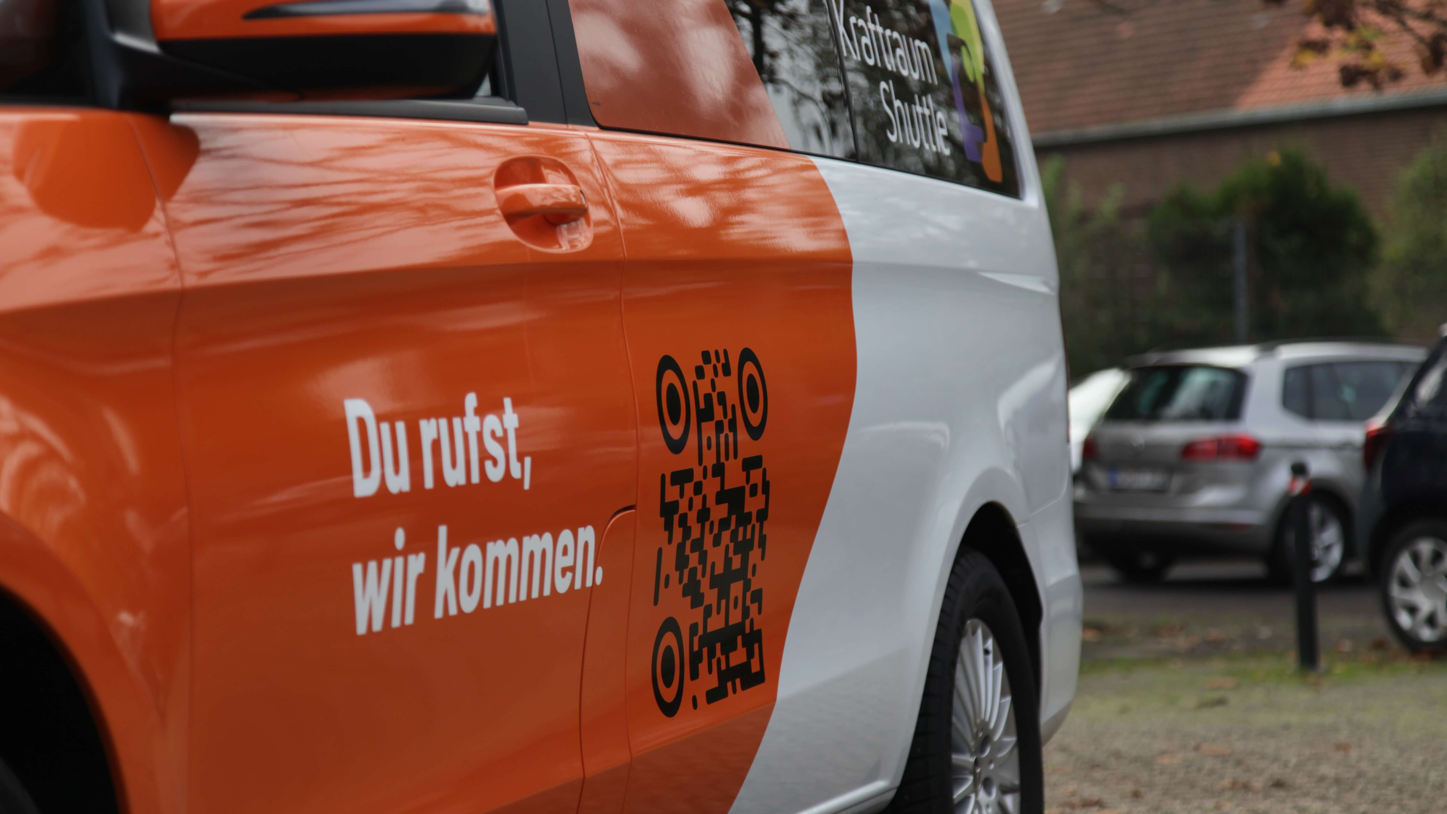 Detail des Kraftraum-Shuttles, seitliche Ansicht der Fahrerseite mit Slogan und QR-Code.