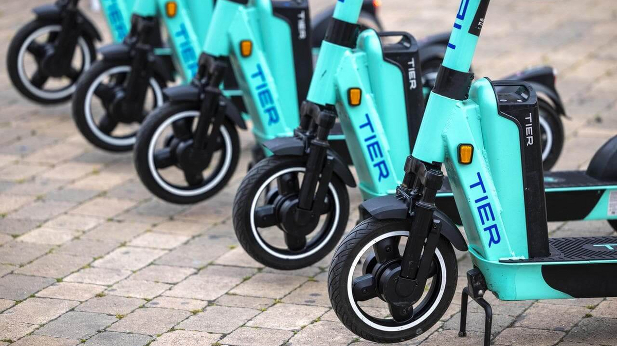 Nahaufnahme mehrere nebeneinander abgestellter E-Scooter des Anbieters TIER