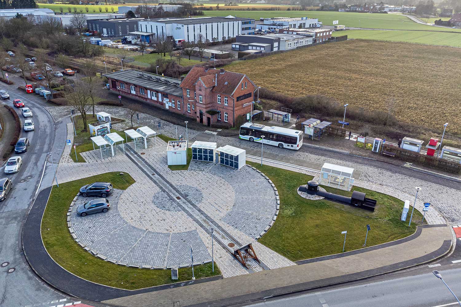 Luftaufnahme der Mobilstation am Bahnhof Borgholzausen mit Blick auf die Gleise, einen Bus und den Platz für E-Autos.