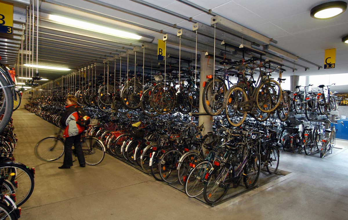 In einem Fahrradparkhaus stehen in großen Blöcken zahlreiche Fahrräder nebeneinander und hängen teilweise von der Decke.