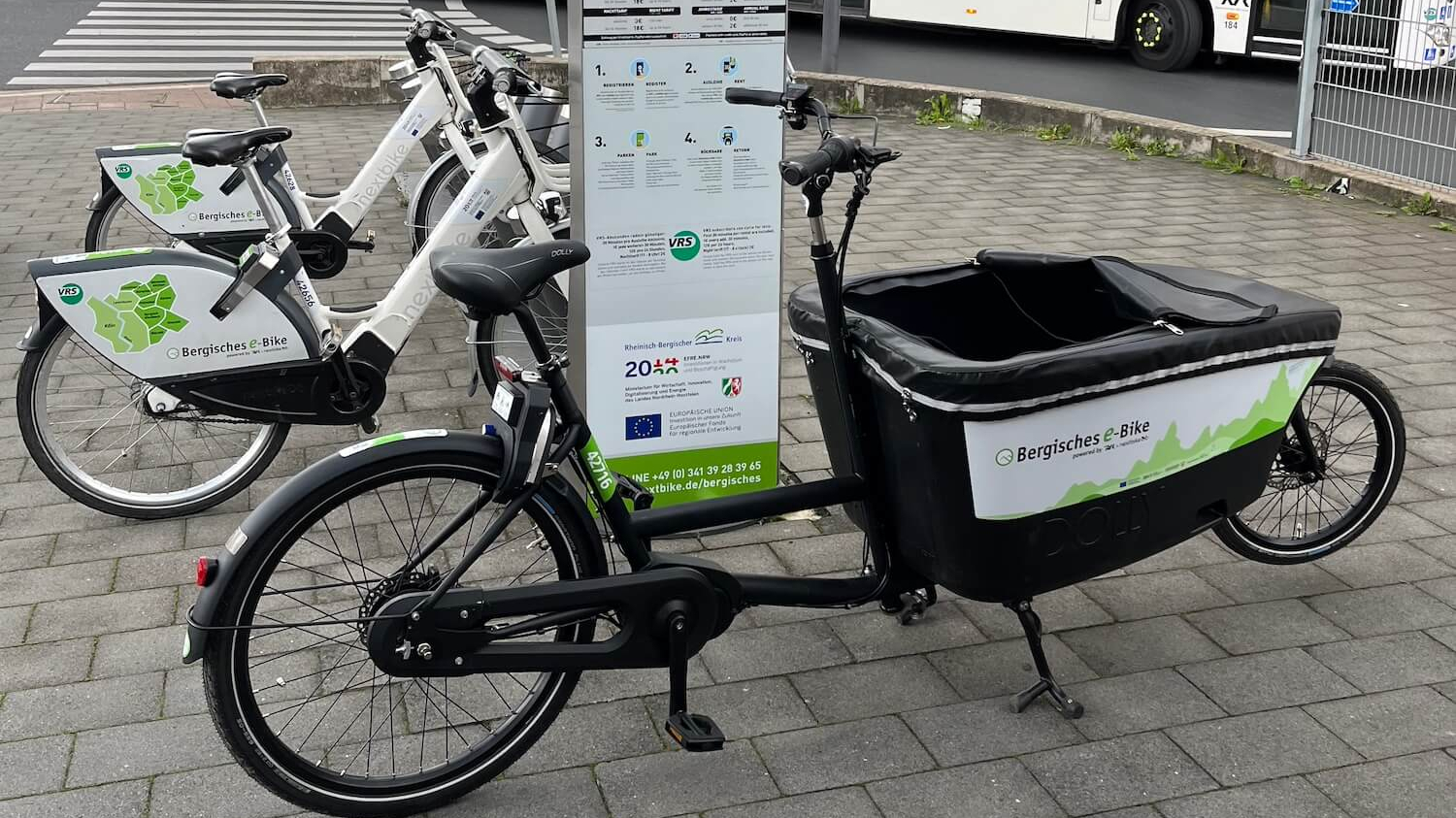 Das Bergische Lastenrad und E-Bike stehen an einer Station.